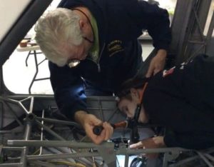 Builder Scott Alperin uses a crimper to secure a flap-controlling cable line for a flap. Assembly Tech Dan Holtz ensures it's set right.
